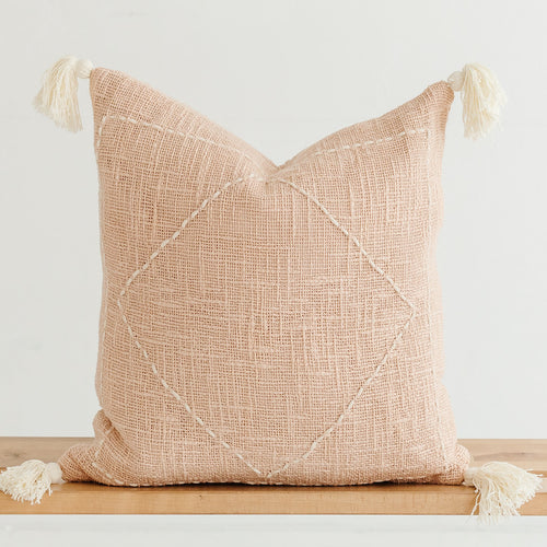 peach throw pillow with hand stitching and tassels